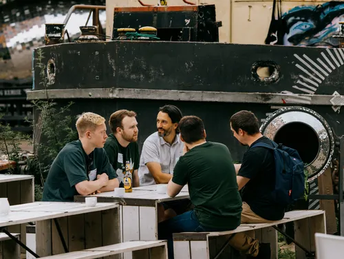 JUXTers chatting around the table in front of a cool looking boat