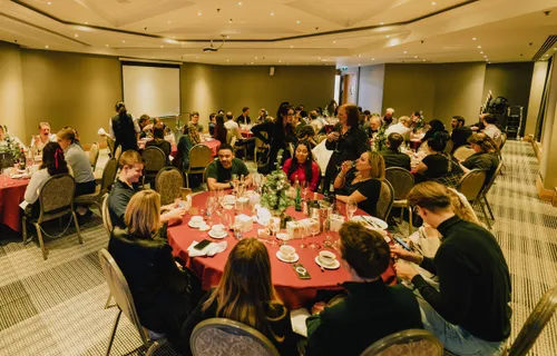 People sitting at round tables inside at JUXT's 2023 Christmas celebration