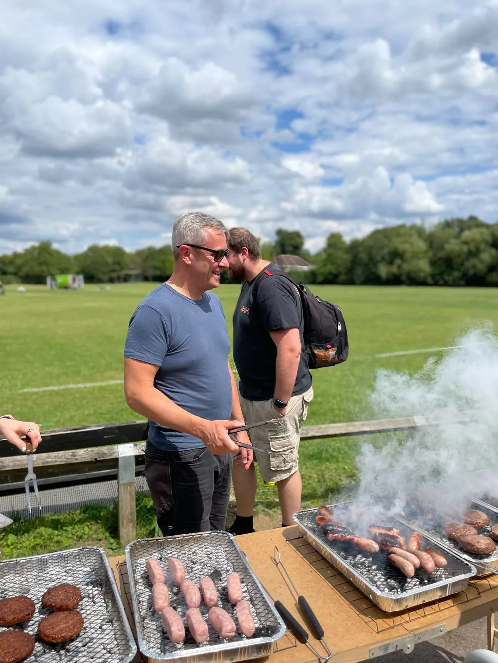 Malcolm with some tongs in front of some BBQs